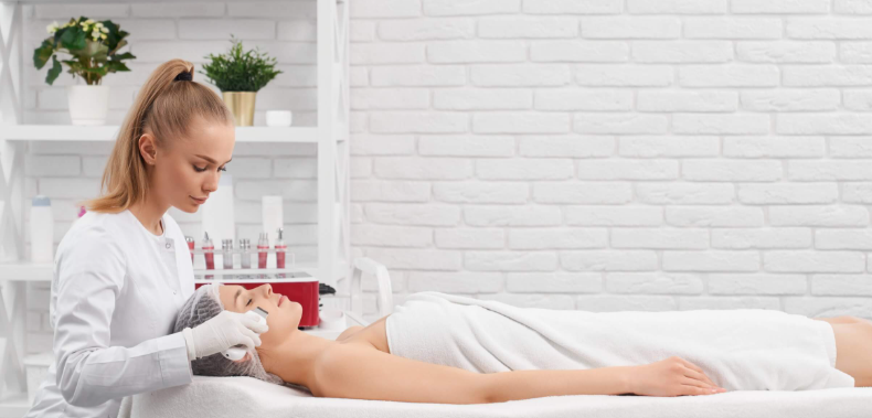 Aesthetician preparing a patient for a facial treatment in a medical aesthetic clinic