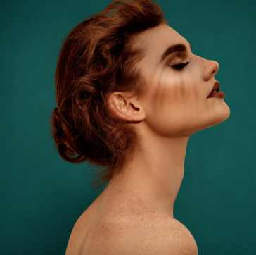 Profile portrait of a woman with her eyes closed against a dark green background