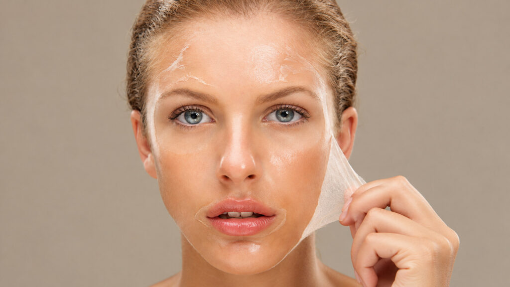 Woman peeling away a thin layer of skin from her face after a chemical peel