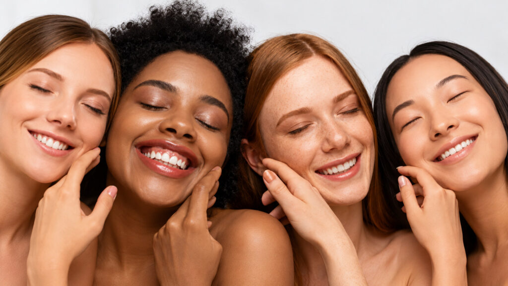 Four smiling women with different skin tones, representing several Fitzpatrick phototypes