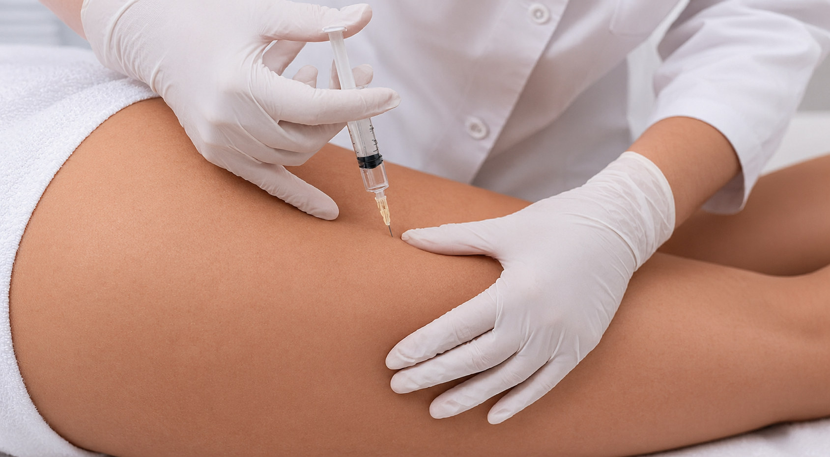 Gloved hands giving a mesotherapy injection on a patient's thigh