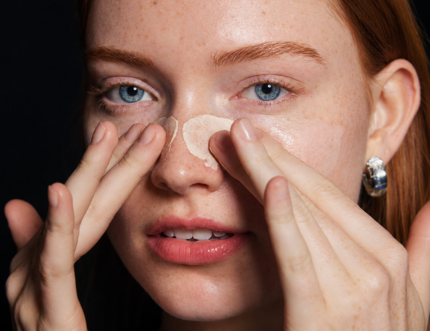 Woman pressing foundation onto her face with her fingertips